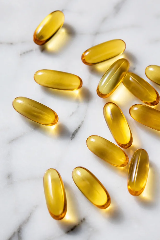Golden omega-3 softgel capsules on marble